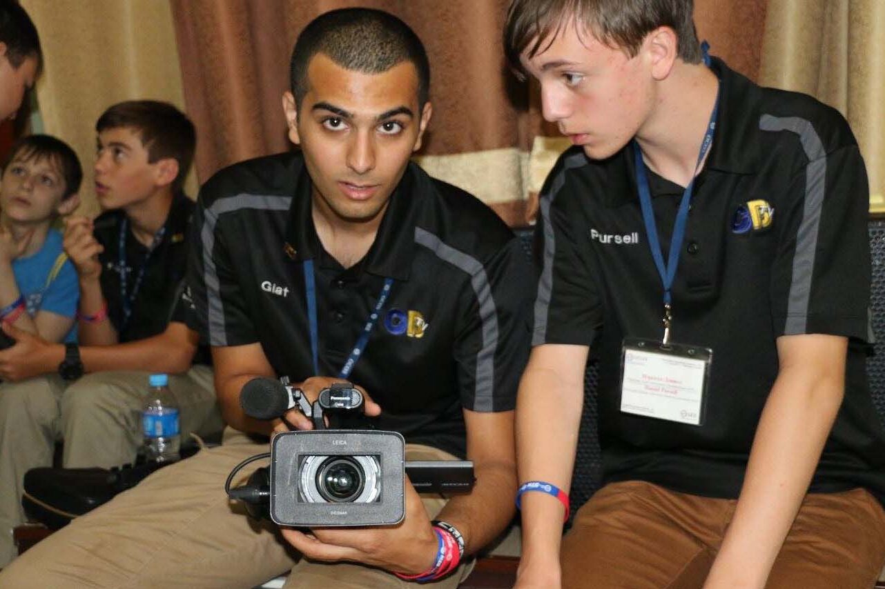 Two young men sit with a camera.